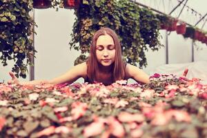 mujer en vestir entre ornamental plantas en un invernadero foto