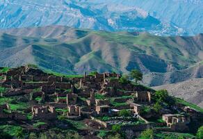 ruins of houses on a mountainside in Kurib, a depopulated village with the only remaining household with an apiary, Dagestan, another village, Chokh, is visible in the distance photo