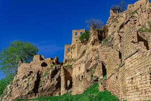 ruins of walls of houses on a cliff in the abandoned village of Gamsutl photo