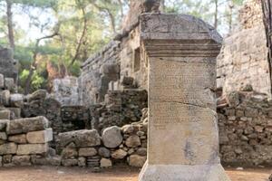 half-erased antique inscription on a stone among the ruins of the ancient city of Phaselis, Turkey photo