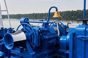 campana, cabrestante y otro mecanismos, pintado azul, en el cubierta de proa de el río barco, de cerca foto