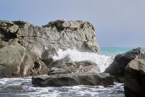 sea surf between coastal rocks with seagulls sitting on them photo