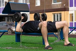 man working out on the street weight machine with dumbbells photo