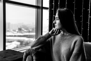 young woman looking thoughtfully out the window on a winter day photo