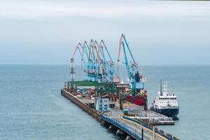 carga atracar con Puerto grúas y amarrado buques en contra el fondo de el abierto mar foto