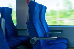 interior de viajero diario al trabajo pasajero tren auto, fila de sillas y un movimiento borroso paisaje fuera de el ventana foto