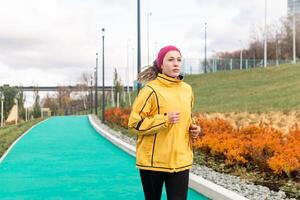 young woman jogging on all-weather running track in urban environment photo