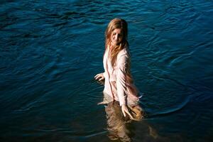 joven mujer se baña en el río disfrutando el frio agua foto