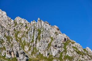 limestone rocky ridge with green vegetation against a blue sky photo