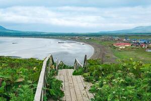 ver de el bahía de yuzhno-kurilsk en el isla de kunashir desde un alto capa, en el primer plano un de madera acera con un escalera foto