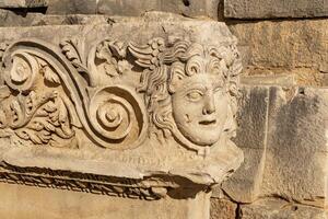 antique frieze with stone-cut mask in the ruins of the ancient city of Myra, Turkey photo