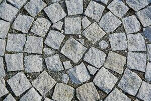 background - fragment of an old sidewalk paved with granite paving stones photo