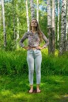 young woman stands on a board with nails doing yoga practice outdoors photo