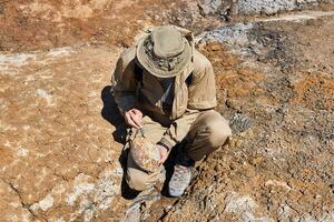 paleontólogo cepillos un redondeado ovoide fósil en un Desierto foto