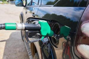 refueling nozzle is inserted into the fuel tank hatch of the vehicle photo