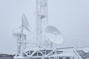 escarchado parabólico antenas y el sótano de el célula torre en el techo de el base radio estación situado en el tierras altas foto