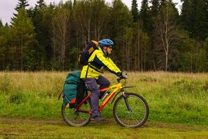 cyclist rides along the edge of the forest on a cloudy day photo