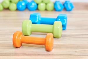 three small rubberized dumbbells of different weights lie on the floor photo