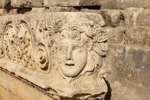 antique frieze with stone-cut mask in the ruins of the ancient city of Myra, Turkey photo