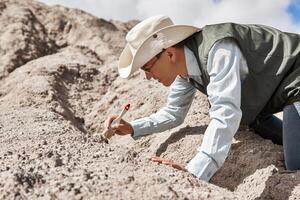 man paleontologist cleans the find with a brush in the desert photo