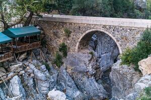 cena Kiosko para turistas siguiente a el antiguo romano puente terminado un sombreado garganta en el kesme bogazi cañón, Turquía foto