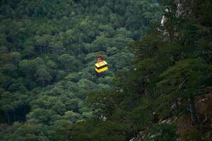 cabin of the aerial tram moves over wooded mountain slopes photo