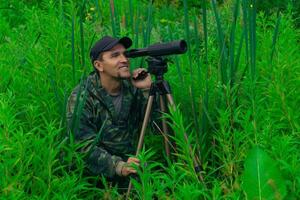 man birdwatcher makes field observation with a spotting scope photo