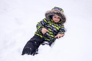 pequeño niño jugando en el nieve en invierno foto