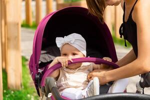 linda bebé en un paseante para un caminar con mamá foto