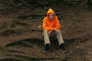 sad teenage girl in a hoodie sits on a natural background photo