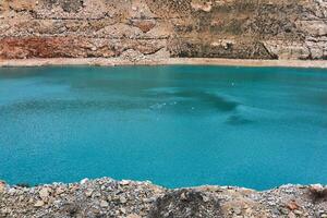 sección de un antiguo caliza cantera con un azul lago con gaviotas a el fondo foto