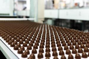 chocolate toppings on the conveyor of a confectionery factory close-up photo