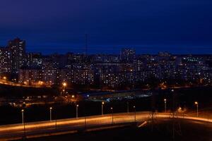 night cityscape with illuminated road in the foreground and residential areas in the background photo