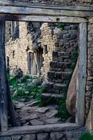 gate in the old abandoned village of Gamsutl, through which a street with ruins of houses is visible photo