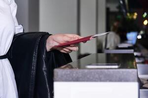 woman traveler's hand holding out passport and air ticket for passport control at the airport photo