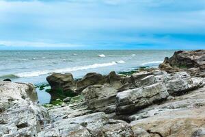 gently sloping rocky shore of the Caspian Sea with rounded rocks and algae on the stones photo