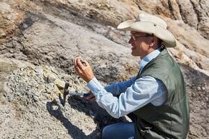hombre geólogo examina un rock muestra en un Desierto zona foto