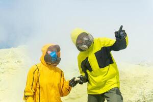 volcanologists on the slope of the volcano collect samples of minerals against the backdrop of smoking sulfur fumaroles photo