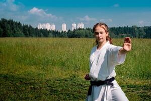 teen girl training karate kata outdoors, performing a strike oi zuki photo