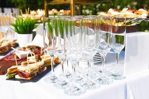 buffet in the open air - empty glasses on the background of cold snacks on the table photo