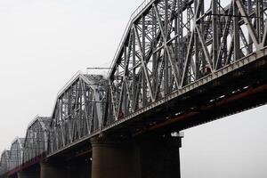 several spans of a railway truss bridge against a cloudy sky photo