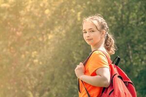 teenager girl in a bright t-shirt with backpack walks in nature photo