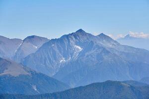 view from a height of mountain peaks with glaciers in a blue atmospheric haze photo