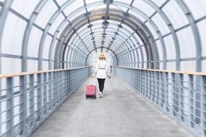 woman tourist with a suitcase goes into the distance along the gallery of the covered passage photo