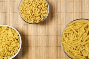 three bowls of dried pasta on a cane tablecloth photo