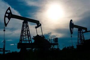 silhouettes of pumpjacks on an oil wells against the background of an alarming sky photo