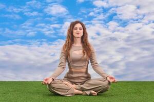 young woman sitting in meditation pose on heavenly background photo