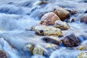 cascada de cascadas de un montaña río entre el cantos rodados, el agua es borroso en movimiento foto