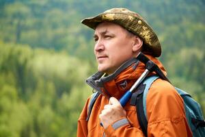 retrato de un hombre geólogo con un mochila y un geológico martillo en contra el enselvado montaña paisaje foto