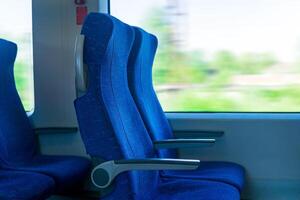 interior de viajero diario al trabajo pasajero tren auto, fila de sillas y un movimiento borroso paisaje fuera de el ventana foto